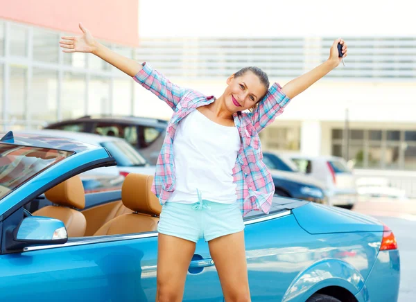 Joven mujer emocional de pie cerca de un convertible con las llaves —  Fotos de Stock