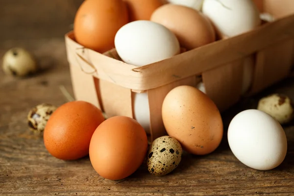 Kip en kwartel eieren op een houten rustieke achtergrond — Stockfoto