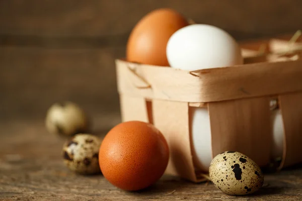 Uova di pollo e quaglia su uno sfondo rustico in legno — Foto Stock
