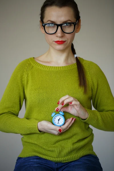 Kleiner blauer Wecker in den Händen einer jungen Frau — Stockfoto