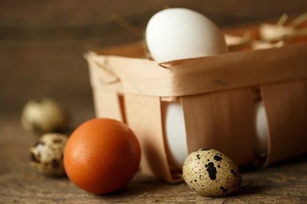 Ovos de galinha e codorniz em um fundo rústico de madeira — Fotografia de Stock