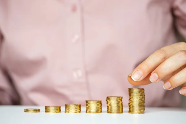 Mano femenina apilando monedas de oro en columnas crecientes — Foto de Stock