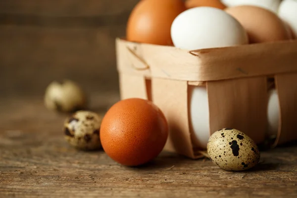 Frango fresco e ovos de codorna em um fundo de madeira — Fotografia de Stock