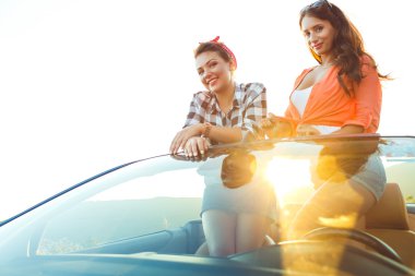 İki genç mutlu kız açık havada cabriolet eğleniyor