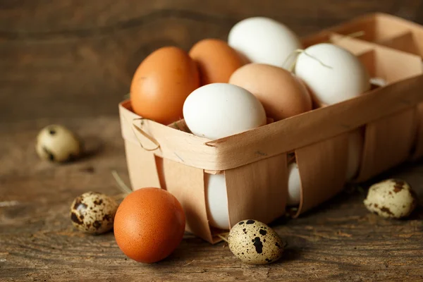 Pollo fresco e uova di quaglia su uno sfondo di legno — Foto Stock