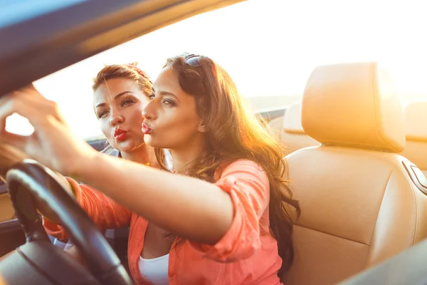 Duas meninas bonitas jovens estão fazendo selfie em um conversível — Fotografia de Stock