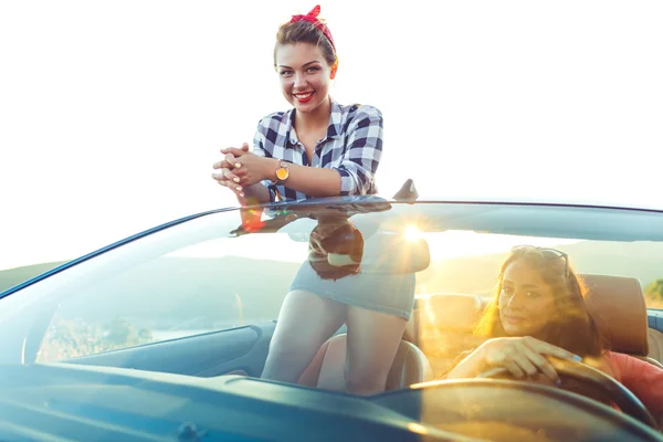 Две молодые счастливые девушки за рулем кабриолета — стоковое фото