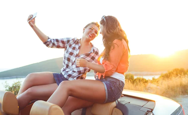 Dos chicas hermosas jóvenes están haciendo una foto tuya en un taxi — Foto de Stock