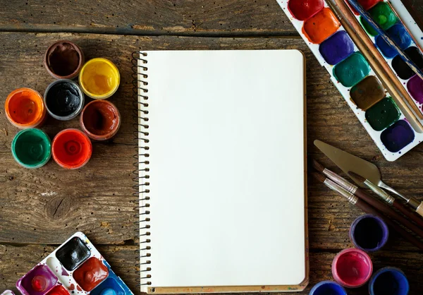Papper, akvareller och paint pensel på trä bakgrund — Stockfoto
