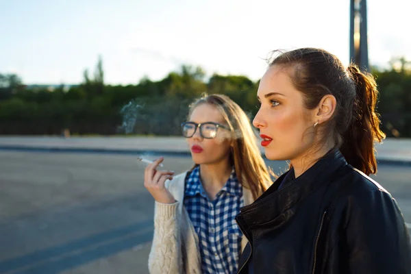 Dos hermosas chicas jóvenes para fumar mientras esperan al aire libre — Foto de Stock