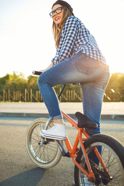 都市の背景には自転車に乗って帽子の素敵な若い女性 — ストック写真