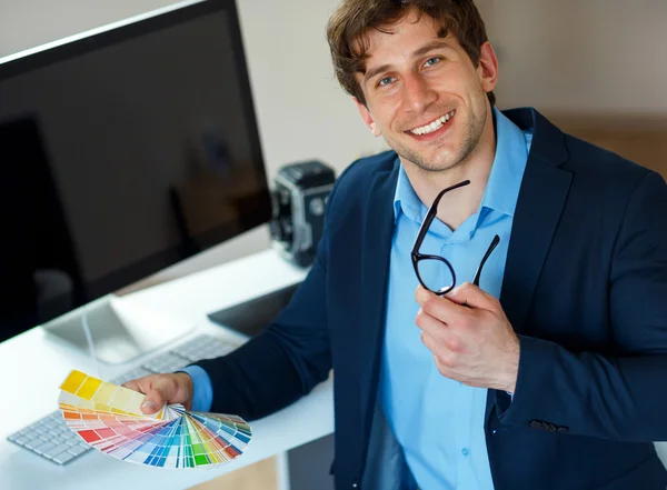 Man looking to a color paint palette at home office
