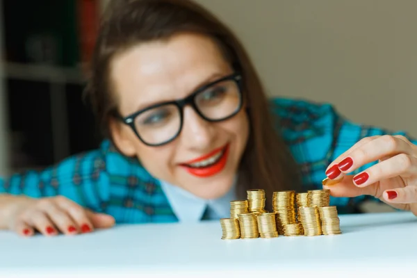 Mujer sonriente apilando monedas de oro en columnas —  Fotos de Stock