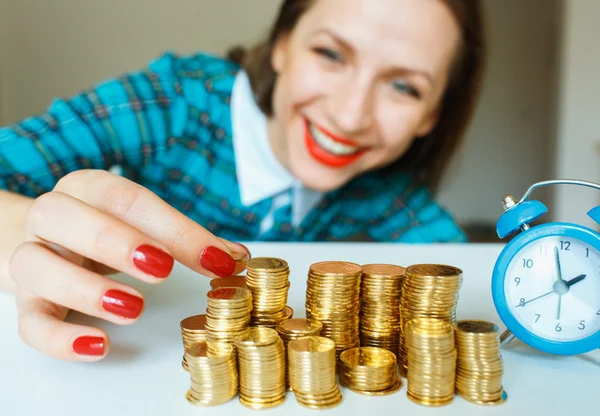 Mujer sonriente apilando monedas de oro en columnas —  Fotos de Stock