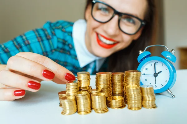 Mujer sonriente apilando monedas de oro en columnas —  Fotos de Stock