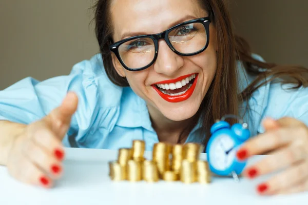 Mulher sorridente empilhando moedas de ouro em colunas — Fotografia de Stock