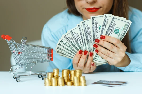 Mujer sosteniendo efectivo, y sobre la mesa hay monedas, tarjeta de crédito y —  Fotos de Stock