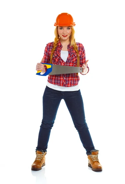 Young funny woman worker in helmet with a saw on a white — Stock Photo, Image