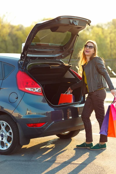 Žena, uvedení její nákupní tašky do kufru auta — Stock fotografie