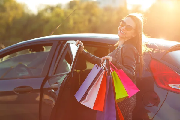 Mosolygó kaukázusi nő a bevásárló szatyrok üzembe az autót — Stock Fotó
