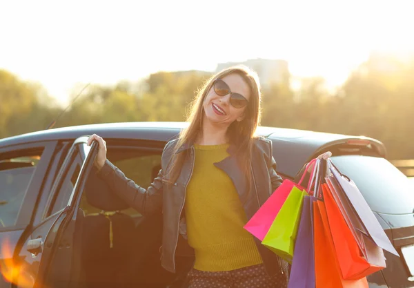 Mosolygó kaukázusi nő a bevásárló szatyrok üzembe az autót — Stock Fotó
