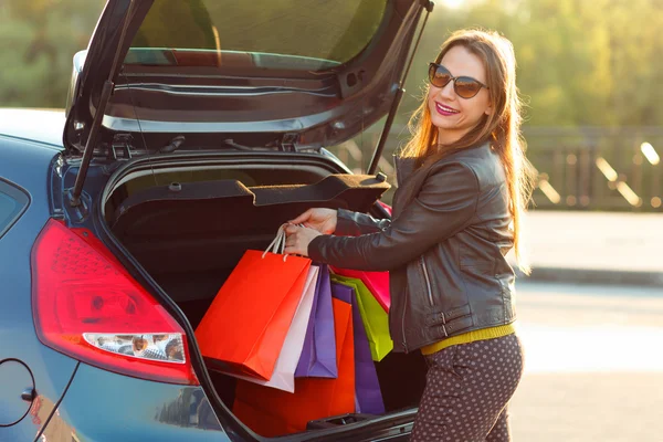 Vrouw haar boodschappentassen ingebruikneming de auto kofferbak — Stockfoto