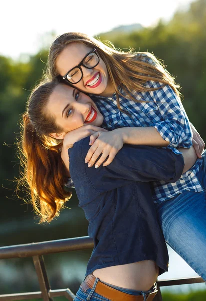 Two playful girls having fun outdoors at sunset light — Stock Photo, Image