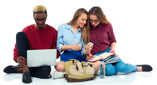 Tres estudiantes sentados con libros, portátil y bolsas aisladas en w —  Fotos de Stock