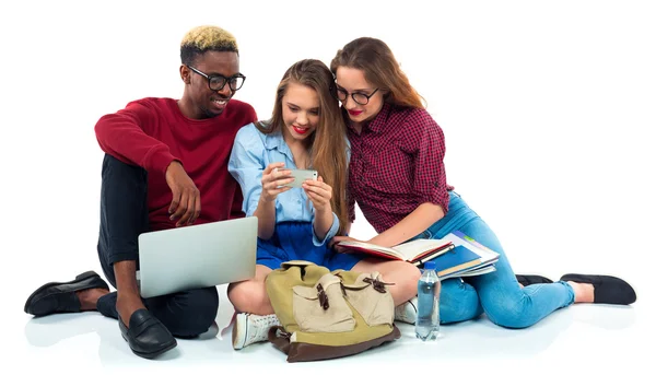 Tre studenti seduti con libri, laptop e borse isolate su w — Foto Stock