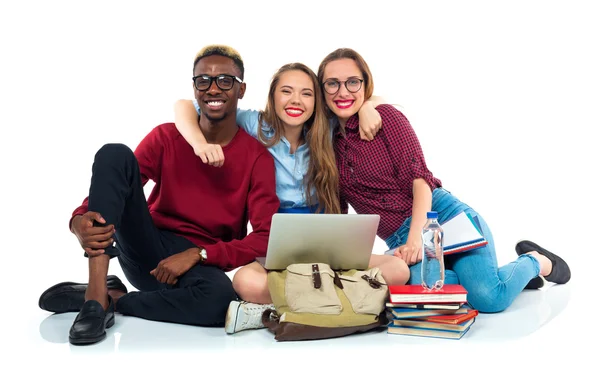 Tres estudiantes sentados con libros, portátil y bolsas aisladas en w —  Fotos de Stock