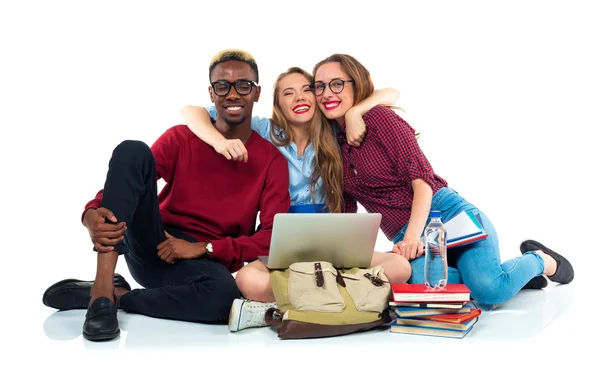 Trois étudiants assis avec des livres, ordinateur portable et sacs isolés sur w — Photo