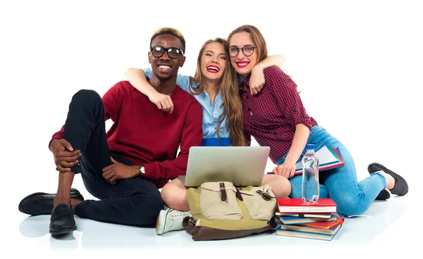 Tre studenti seduti con libri, laptop e borse isolate su w — Foto Stock