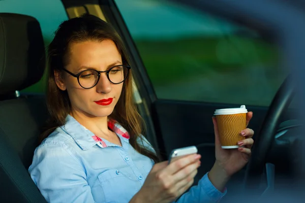 Empresaria que envía un mensaje de texto y beber café mientras d — Foto de Stock