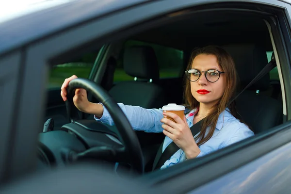 Mujer joven con café para ir conduciendo su coche —  Fotos de Stock