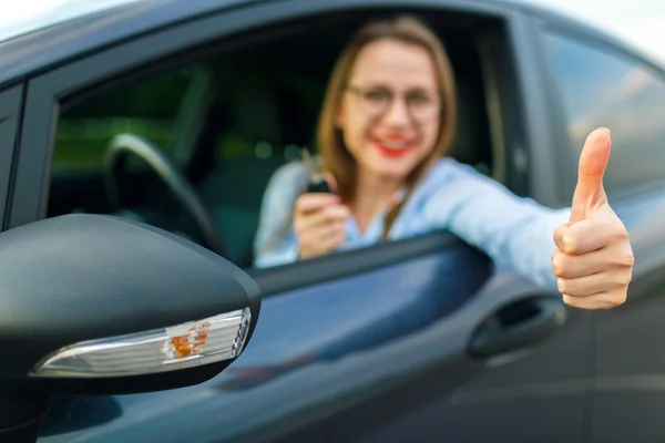 Giovane donna felice seduta in macchina con le chiavi in mano e — Foto Stock