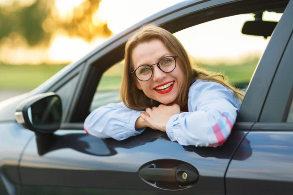 Jovem mulher feliz sentada em um carro — Fotografia de Stock