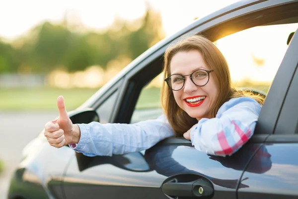 親指で車に座っている若い幸せな女 — ストック写真
