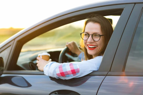 Mujer joven con café para ir conduciendo su coche — Foto de Stock