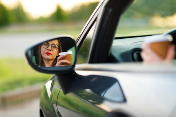 Mujer joven con café para ir conduciendo su coche —  Fotos de Stock