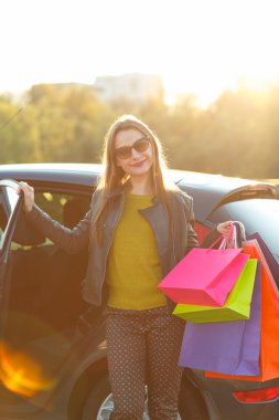 Alışveriş çantalarını arabaya koyarak gülümseyen beyaz kadın