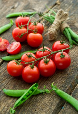 Kuşkonmaz ve ahşap backgro üzerinde yeşil bezelye ile taze domates