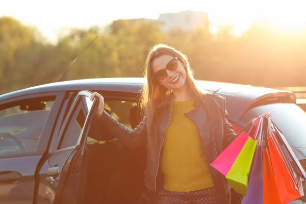 Lachende Kaukasische vrouw haar boodschappentassen ingebruikneming in de auto — Stockfoto