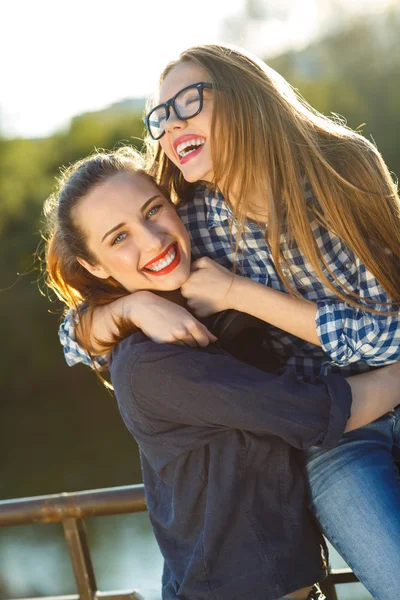 Dos chicas juguetonas divirtiéndose al aire libre al atardecer —  Fotos de Stock