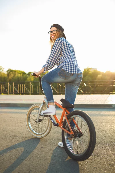 都市の背景には自転車に乗って帽子の素敵な若い女性 — ストック写真