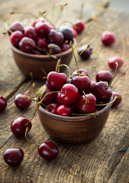Ripe cherries in a clay bowl on wooden background — Stock Photo, Image