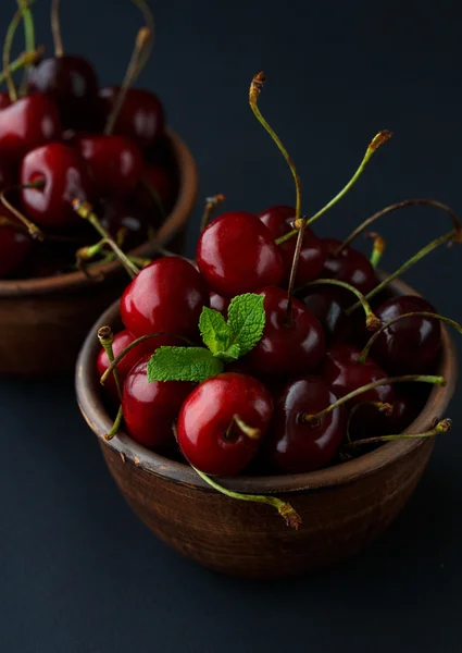 Ripe cherries in a clay bowl on black background — Stock Photo, Image