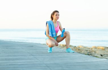 Güneşli sabah sahilde, atletik kadın çalıştırdıktan sonra dinlenme