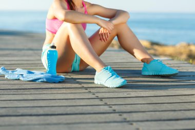 Güneşli sabah sahilde, atletik kadın çalıştırdıktan sonra dinlenme