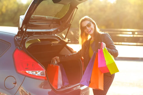 Lachende Kaukasische vrouw haar boodschappentassen ingebruikneming de auto t — Stockfoto