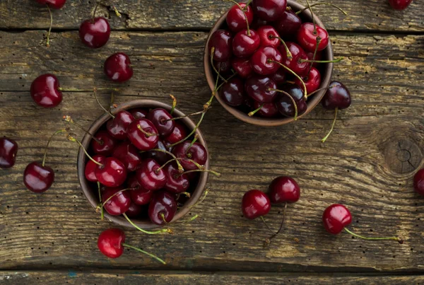 Ripe cherries in a clay bowl on a  wooden background — Stock Photo, Image